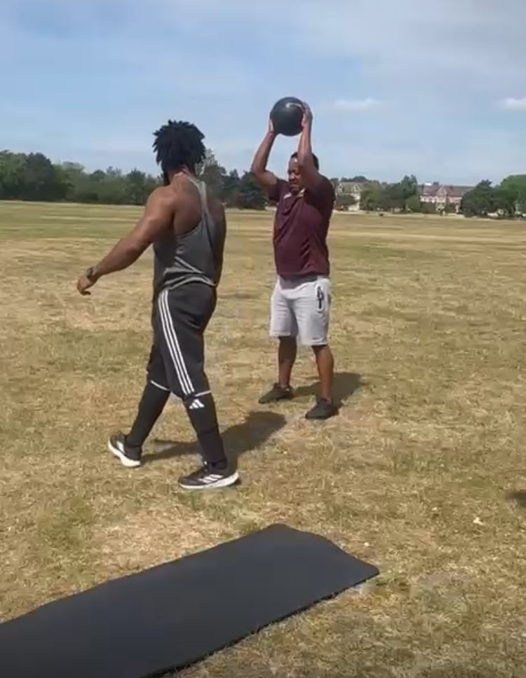 Ryan Compass coaching a client with a medicine ball in a South London park